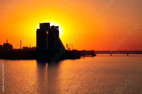 Silhouette of a skyscraper Sail and  Old bridge on a sunset background,  on the Dnieper River in the Dnipro city (Dnepropetrovsk, Dnepr),   Ukraine. 