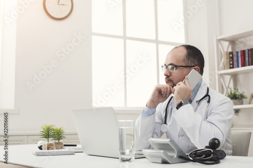 Serious doctor talking on phone with his patient