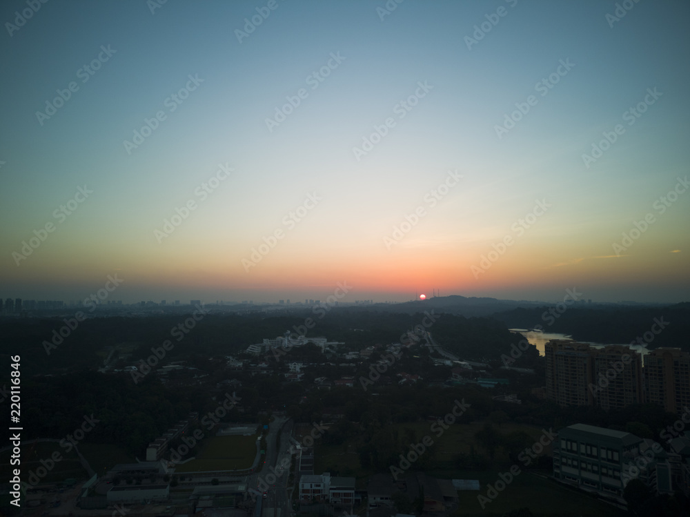 Aerial shot of a soft orange glowing sunset against a cloudless blue sky