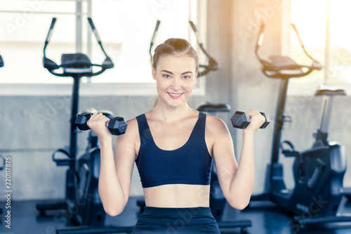 Fitness, sport, training and lifestyle concept - Young women flexing muscles in fitness gym center. © Phutthiseth