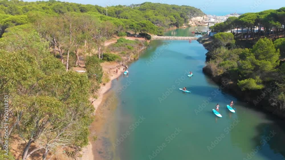 Aerial - Group of women practicing paddle surf in a beautiful river Aerial - Group of women practicing paddle surf in a beautiful river