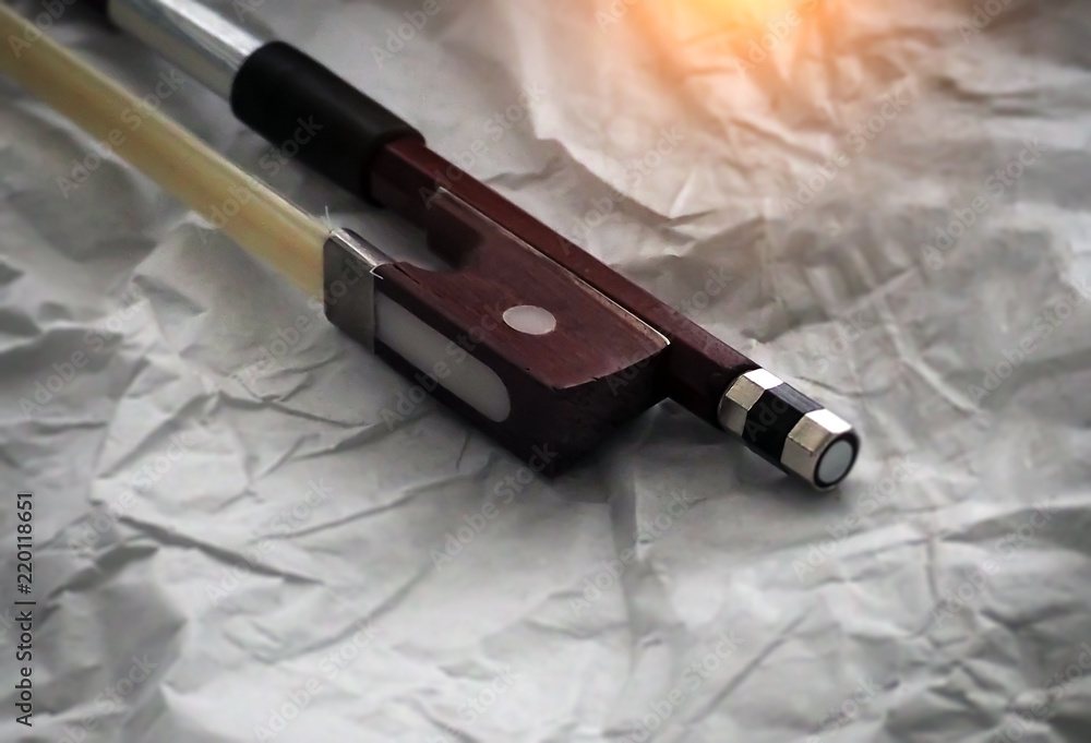 Naklejka premium In selective focus of violin bow frog and violin bow screw,the end part of a stringed musical instrument's bow,blurry light around