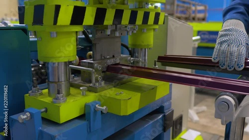 The machine cuts a sheet of metal. Factory for the creation of metal roofing. Rolling metal in the machine to create a metal roof. photo