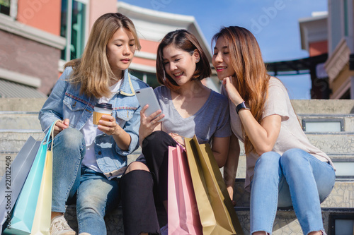 Attractive beautiful asian woman using a smartphone while shopping in the city. Happy young asian teenage at urban city while taking self portraits with her friends together with a smartphone.