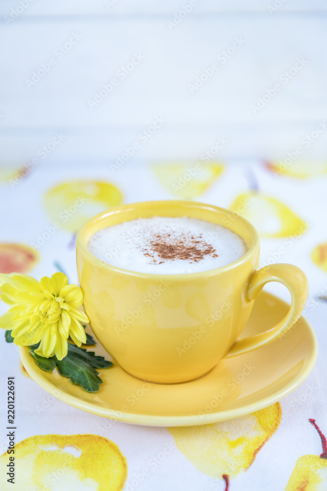 Yellow cup with coffee cappuccino, cinnamon and yellow chrysanthemum on a light background. Free space Yellow cup with coffee cappuccino, cinnamon and yellow chrysanthemum on a light background. Free space