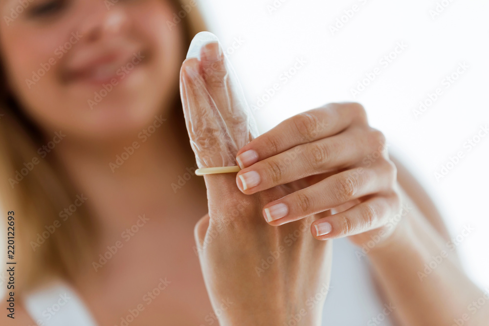 Stockfoto med beskrivningen Beautiful young woman putting condom on her  fingers over white background. | Adobe Stock