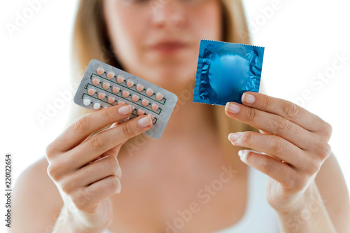 фотографія Beautiful woman showing condom and contraceptive pills over white background