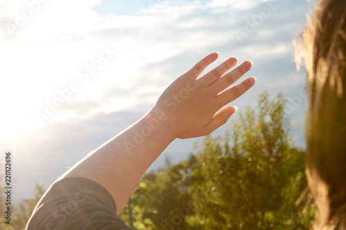 A young woman protects her eyes and skin from the sun with her hands