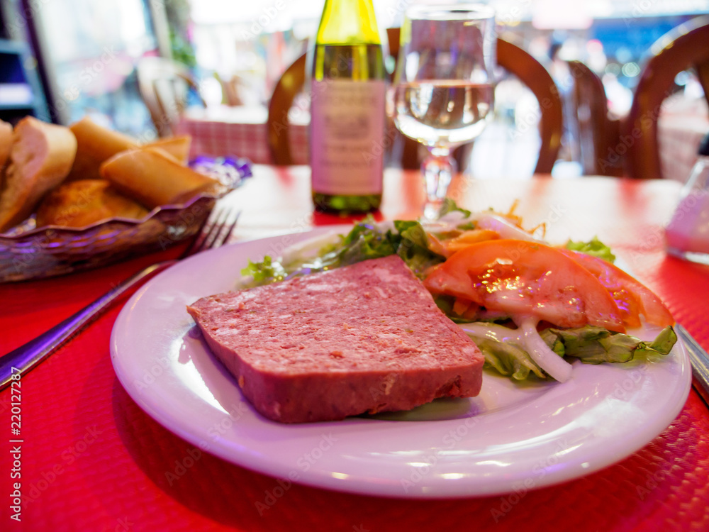 Wide closeup of a plate of Country Pate, also known as Pate de Campagne, with wine and bread at a local restaurant. Paris, France. Travel and cuisine.