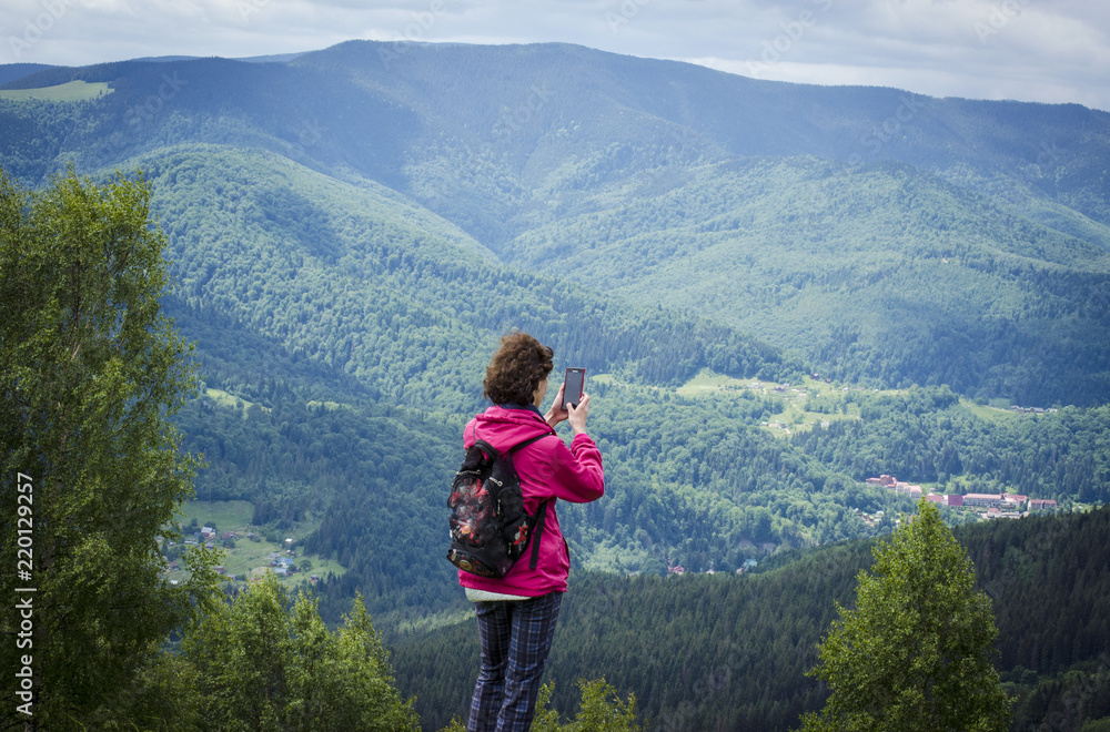 Naklejka premium girl in the mountains shoots on the phone