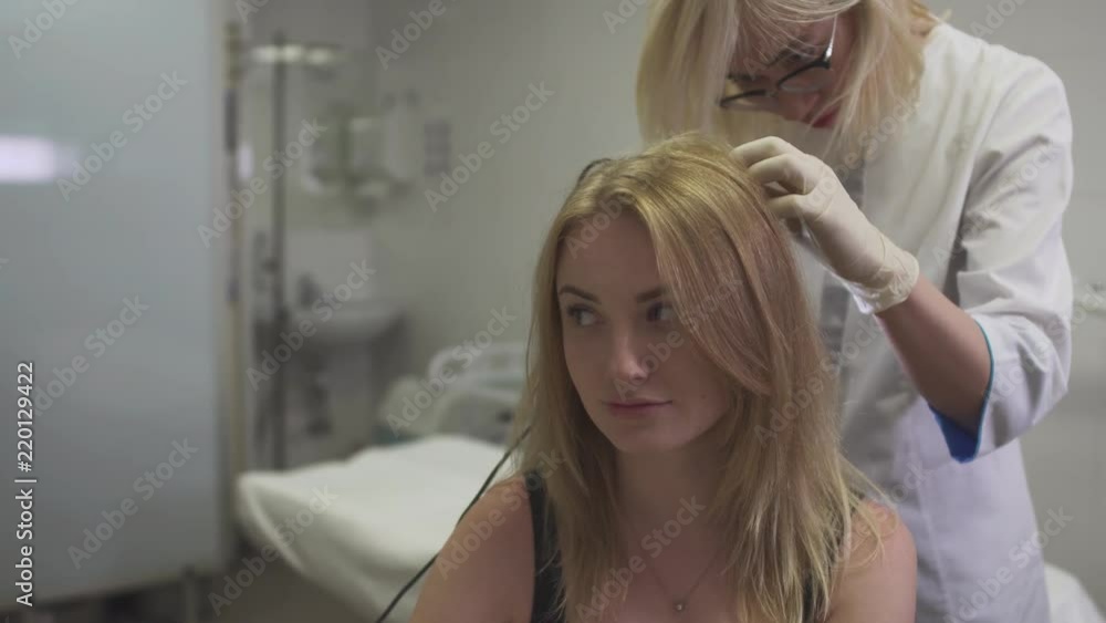 Dermatologist examines the skin on the head of the girl Dermatologist examines the skin on the head of the girl