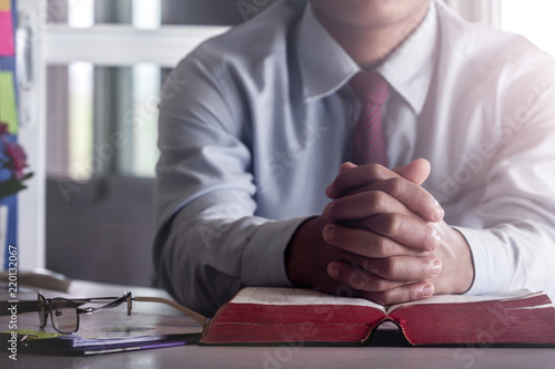 Medical doctor praying on bible with on desk at office