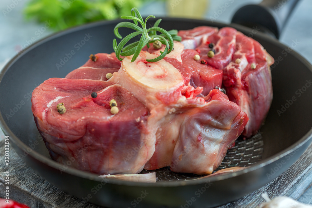 Piece of raw beef shank for Osso Buco and a sprig of rosemary. Piece of raw beef shank for Osso Buco and a sprig of rosemary.
