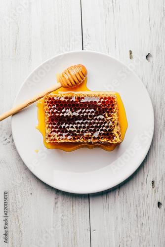 Honeycomb on white plate with honey dipper