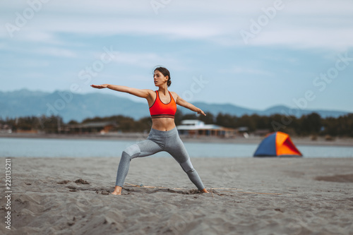 Young woman practicing yoga on the beach
