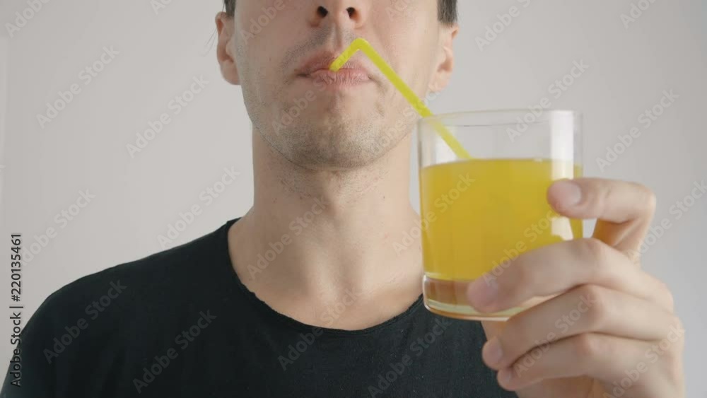 young man drinks refreshing orange soda through a tube at white background young man drinks refreshing orange soda through a tube at white background