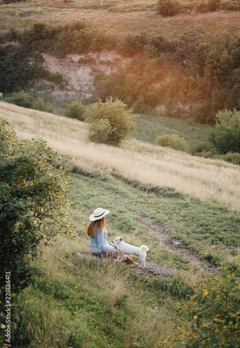 Foto in autumn a girl in a hat is walking with a white dog