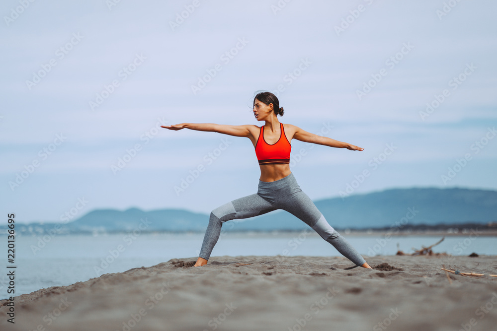 Young woman practicing yoga on the beach