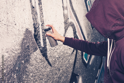 Graffiti artist with aerosol spray bottle near the wall photo
