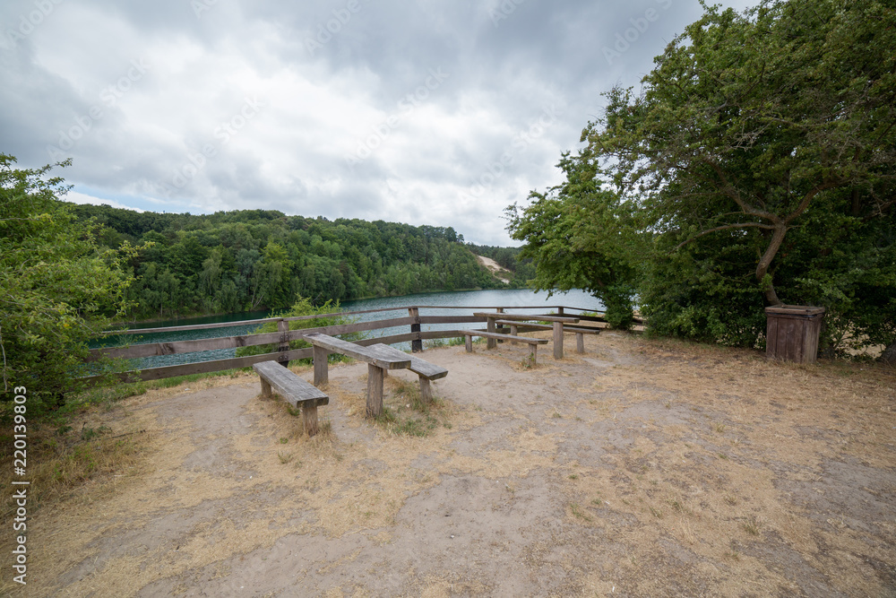 Tables with benches on picnic area near lake in park
