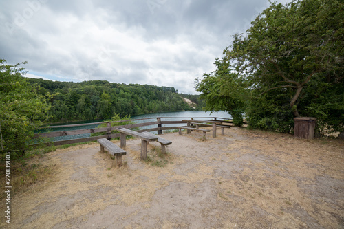 Tables with benches on picnic area near lake in park