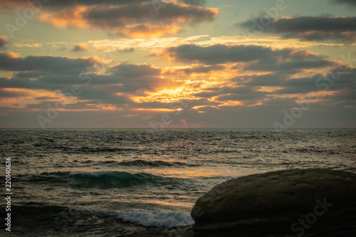Sunset at beach with waves and rocks