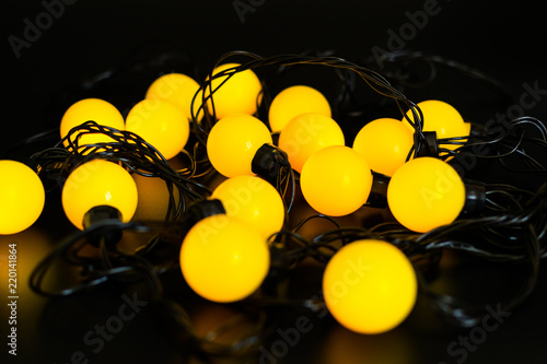 yellow glowing garland stacked on a black background with light reflection