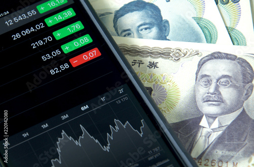 Japanese money, bills and smartphone, mobile trading on the stock exchange.