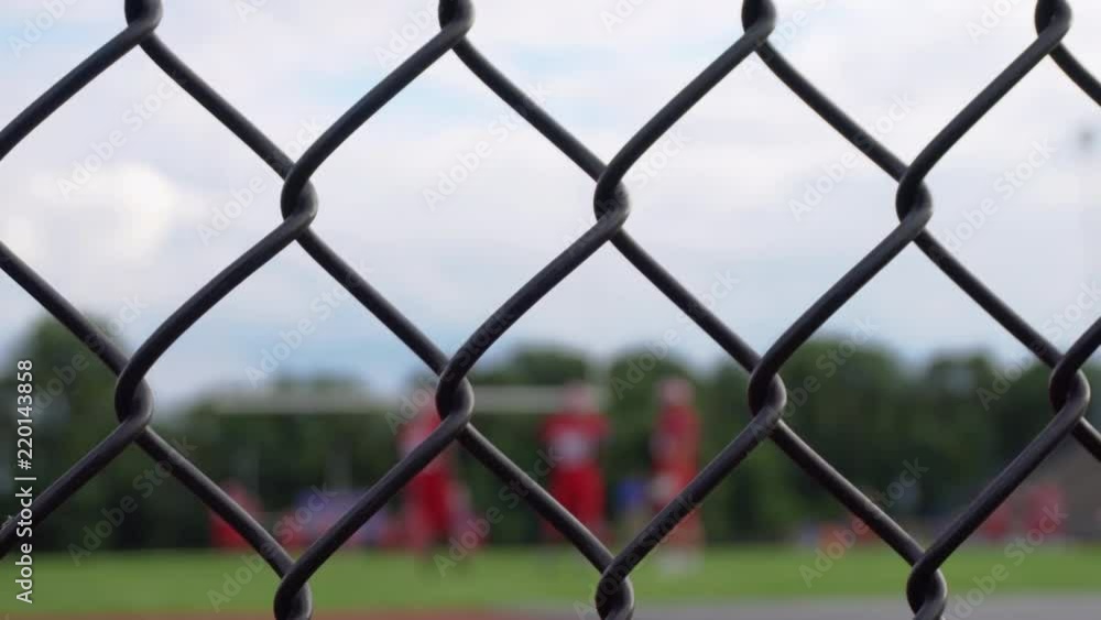 Football players practicing behind a stadium fence, out of focus Football players practicing behind a stadium fence, out of focus