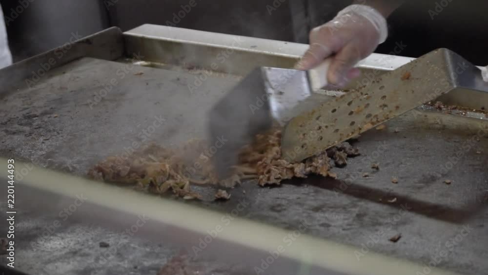 Chopping a cheese steak on a griddle, in slow motion Chopping a cheese steak on a griddle, in slow motion