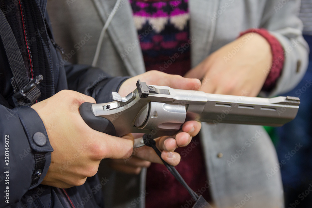 Man is holding a revolver in a gun shop. Sales
