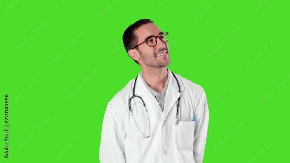 Confident young doctor looking up agains green background Confident young doctor looking up agains green background