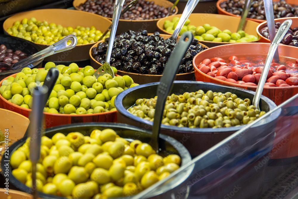 Bowls of green and black olives on display on a market stall