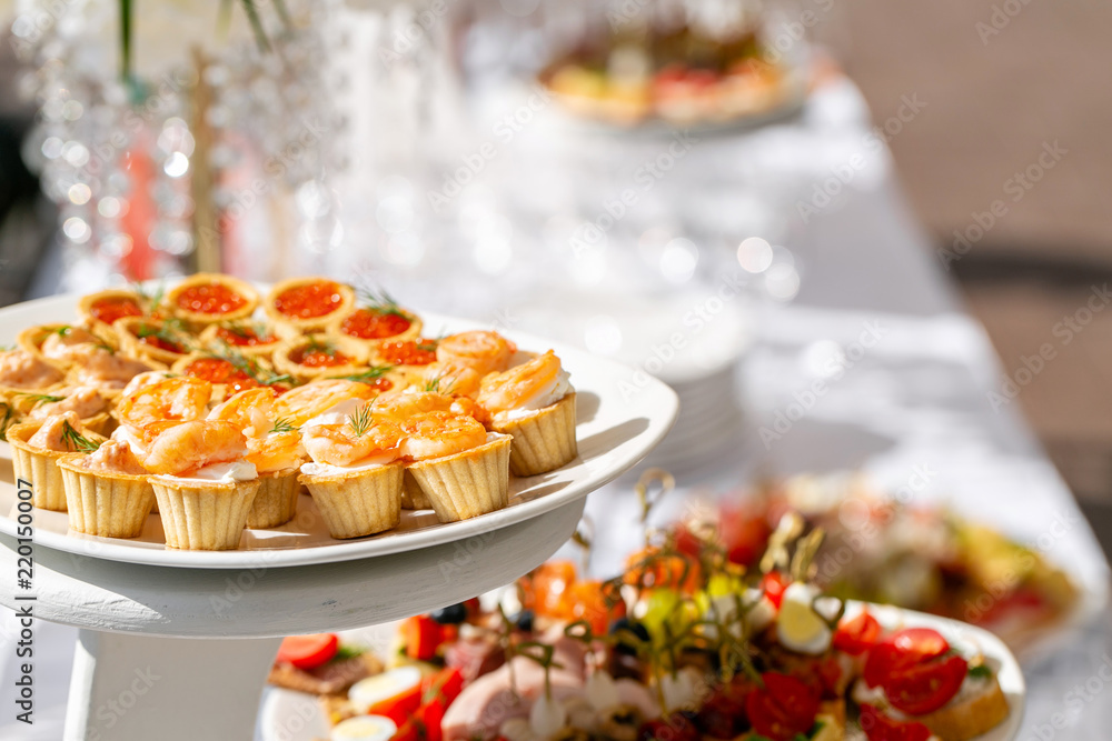 solemn banquet. Lot of glasses champagne or wine on the table in restaurant. buffet table with lots of delicious snacks. canapes, bruschetta, and little desserts on wooden plate board solemn banquet. Lot of glasses champagne or wine on the table in restaurant. buffet table with lots of delicious snacks. canapes, bruschetta, and little desserts on wooden plate board