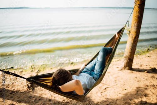 Woman relaxing in a hammock on the beach  a hot sunny day