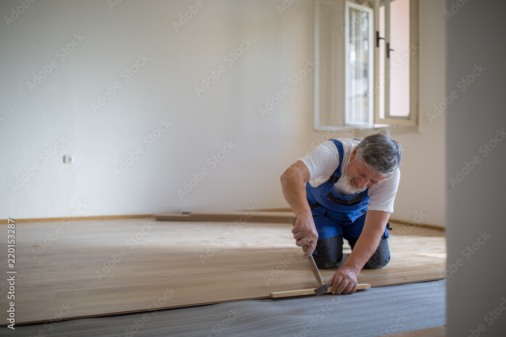 DIY, repair, building and home concept - close up of male hands lying parquet floor board/laminate flooring (shallow DOF; color toned image) DIY, repair, building and home concept - close up of male hands lying parquet floor board/laminate flooring (shallow DOF; color toned image)
