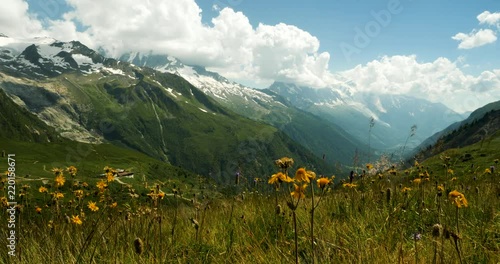 footage of the mont blanc massif near chamonix in the french alps showing clouds moving against blue summer sky and green alpine meadows