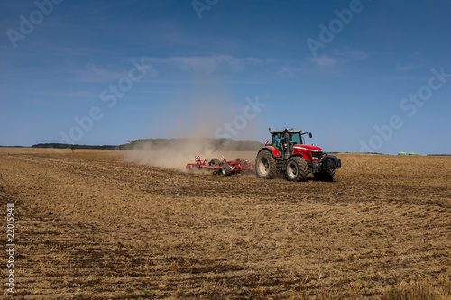 Roter Traktor pflügt Feld im Spätsommer