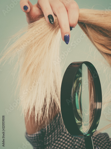 Woman looking at hair through magnifying glass