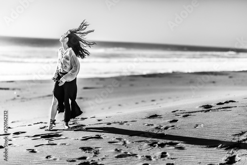 Beautiful young girl walking along the beach sand dunes step by step letting it footprints in the sand. An amazing wild beach during a sunny day at sunset time in Topocalma Beach, Puertecillo, Chile photo