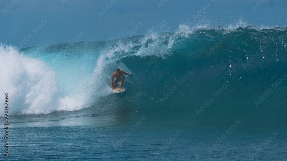 Obraz premium CLOSE UP: Pro extreme surfer rides a breathtaking emerald wave in sunny Tahiti.
