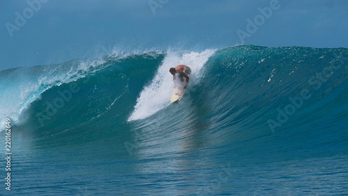CLOSE UP: Pro male surfer stands up on his surfboard and catches a big wave.