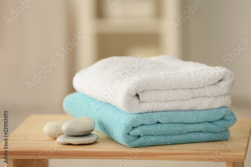 Clean towels and stones on table against blurred background