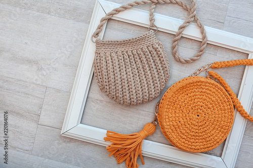 Knitted bags and space for design on wooden background, flat lay