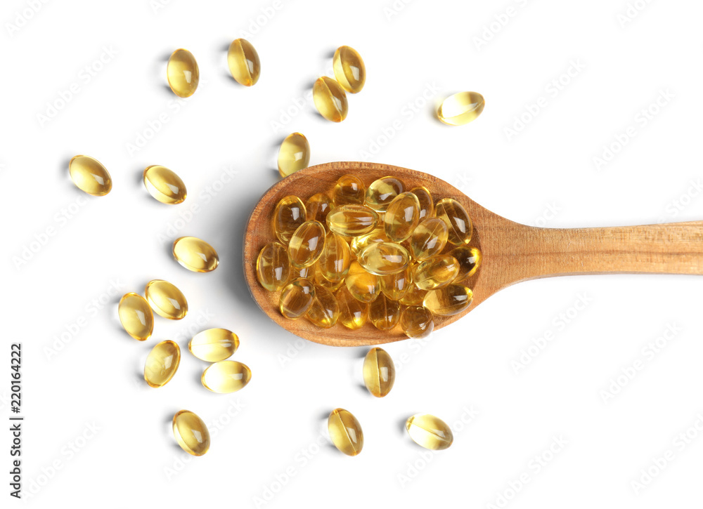Spoon with cod liver oil pills on white background, top view