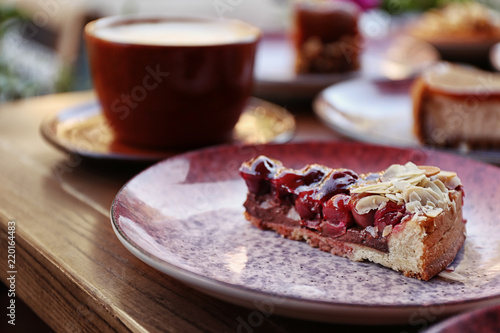 Plate with slice of cherry cake on wooden table