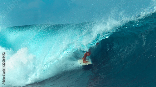 CLOSE UP: Unrecognizable male tourist surfing a cool turquoise barrel wave.