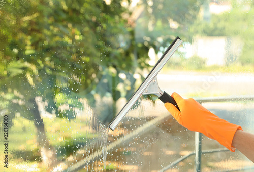 Janitor cleaning window with squeegee indoors, closeup
