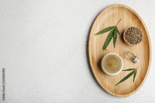 Flat lay composition with hemp lotion and space for text on white wooden background