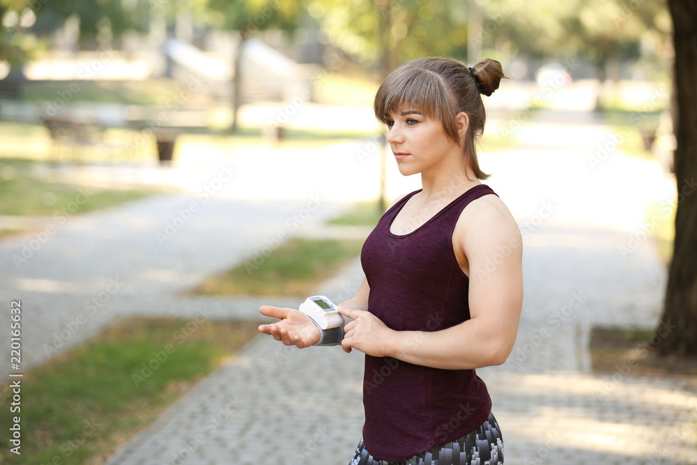 Young woman checking pulse after workout in park Young woman checking pulse after workout in park